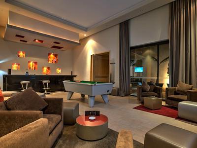 Area lounge moderna in hotel con tavolo da biliardo, divani e illuminazione d'ambiente.
