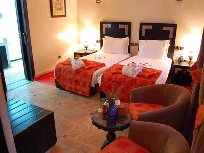 Cozy hotel room with two single beds, warm lighting, and a seating area.