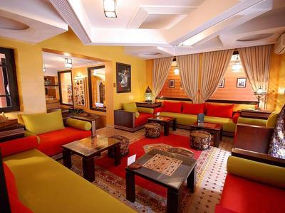 Cozy hotel lounge with red and yellow sofas, wooden tables, and warm lighting.