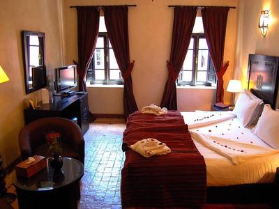 Cozy hotel room with two single beds, dark curtains, and warm lighting.