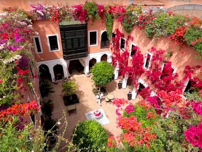 Courtyard with colorful flowers, Mediterranean architecture, and seating area.