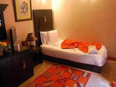 Cozy hotel room with single bed, dark wood furniture, and colorful rug.