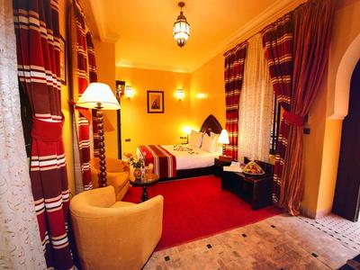 Cozy hotel room with warm lighting, red carpets, and oriental curtains.