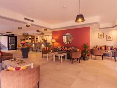 Jasna lobby hotelowa z wygodnymi fotelami, sofami, stolikami i dekoracyjną ścianą.
