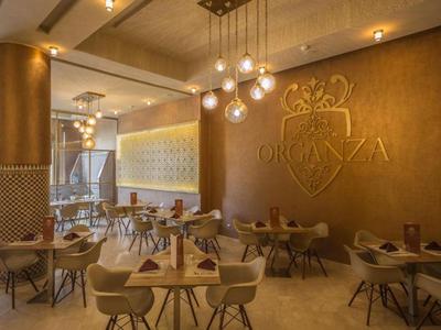 Nowoczesna restauracja hotelowa z wygodnymi krzesłami, ciepłym oświetleniem i stylowymi drewnianymi stołami.