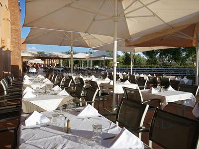 Venkovní restaurace s bílými ubrusy a slunečníky v hotelu.