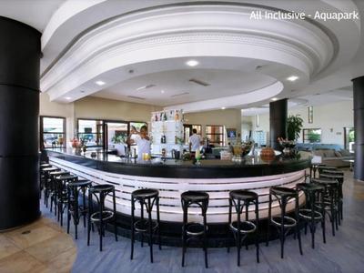 Nowoczesny bar hotelowy z okrągłym kontuarem i licznymi stołkami pod sklepieniem.