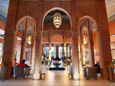 Großer Hotel-Lobbybereich mit hohen Bögen, rotem Backstein und Sitzgelegenheiten.
