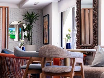 Helles Hotelzimmer mit gemütlicher Sitzgruppe, Holzmöbeln und großen Spiegeln.