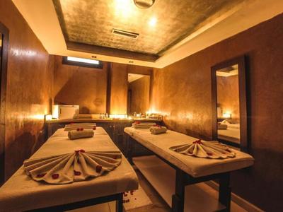 Gemütlicher Spa-Raum mit zwei Massageliegen, gedämpftem Licht und warmen Holztönen.