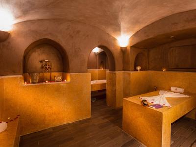 Warmer Wellnessraum mit Holzbänken, Steinmauern und gedämpfter Beleuchtung.