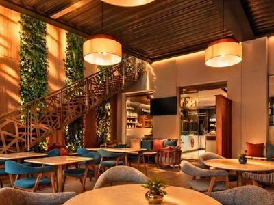 Modernes Hotelinnendesign mit Holzmöbeln, grünen Pflanzen und warmem Licht.