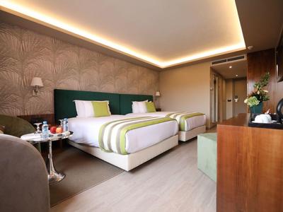 Nowoczesny pokój hotelowy z dwoma łóżkami, stylowym oświetleniem i jasnymi drewnianymi podłogami.
