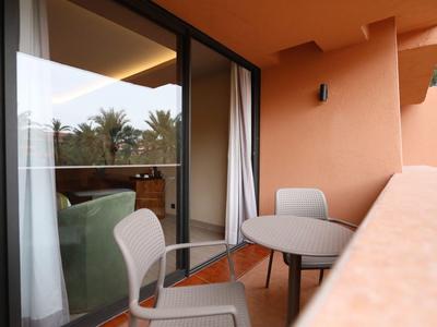 Balkon z stołem i krzesłami, widok na tropikalne rośliny, część hotelu.
