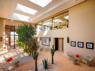 Spacious, bright hotel lounge area with plants, seating, and abundant natural light.