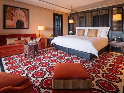 Hotel room with large bed, colorful carpet, and cozy seating area.