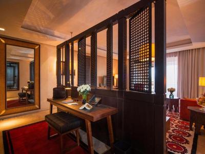 Modern hotel room area with wooden partitions, desk, mirror, and cozy sitting area.