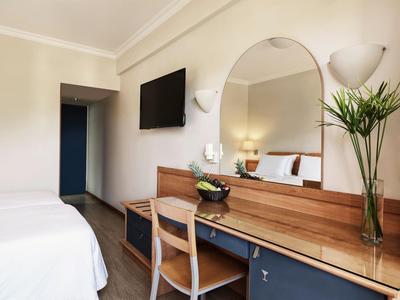 Modernes Hotelzimmer mit Schreibtisch, Stuhl, großem Spiegel und Flachbildfernseher.