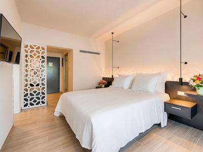 Modernes Hotelzimmer mit großem, weiß bezogenem Doppelbett und schwebenden Nachttischen.