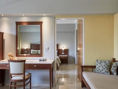 Zimmer mit Schreibtisch, Stuhl und angrenzendem Schlafzimmer mit Doppelbett.