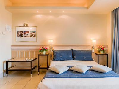Gemütliches Hotelzimmer mit Doppelbett, blauen Kissen, Nachttischen und warmem Licht.