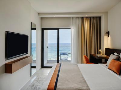 Modernes Hotelzimmer mit Meerblick, großem Bett, TV und Schreibtisch an der Seite.