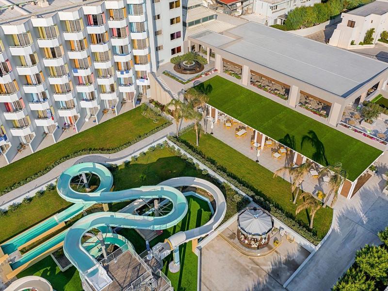 Luftaufnahme eines Hotels mit Wasserrutschen, Pool und modernen Außenanlagen.
