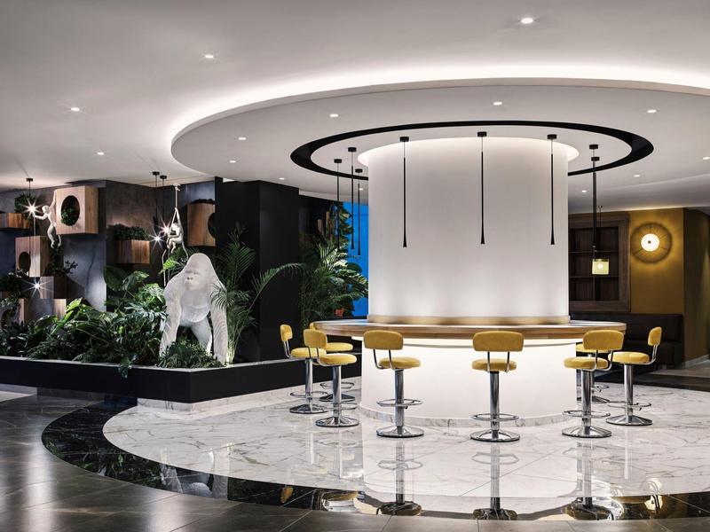 Moderne Hotelbar mit runden Hockern und dekorativer Statue in eleganter Atmosphäre