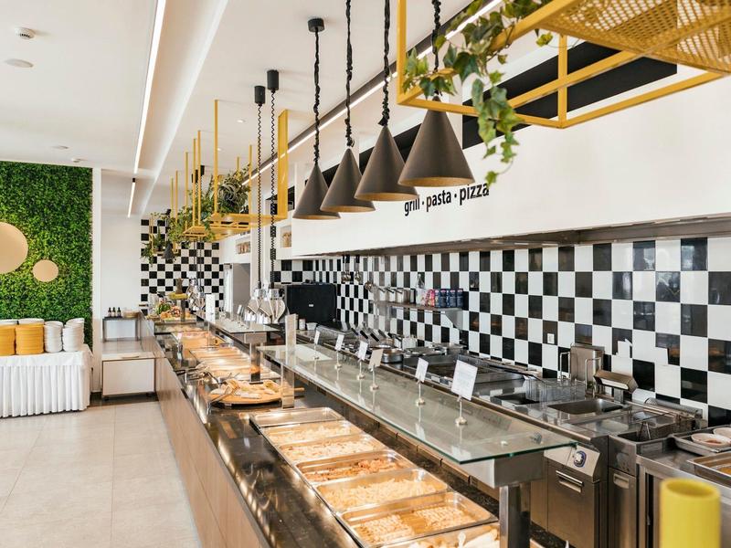 Moderne Hotelküche mit schwarzem und weißem Schachbrettmuster an der Wand und hängenden Lampen.