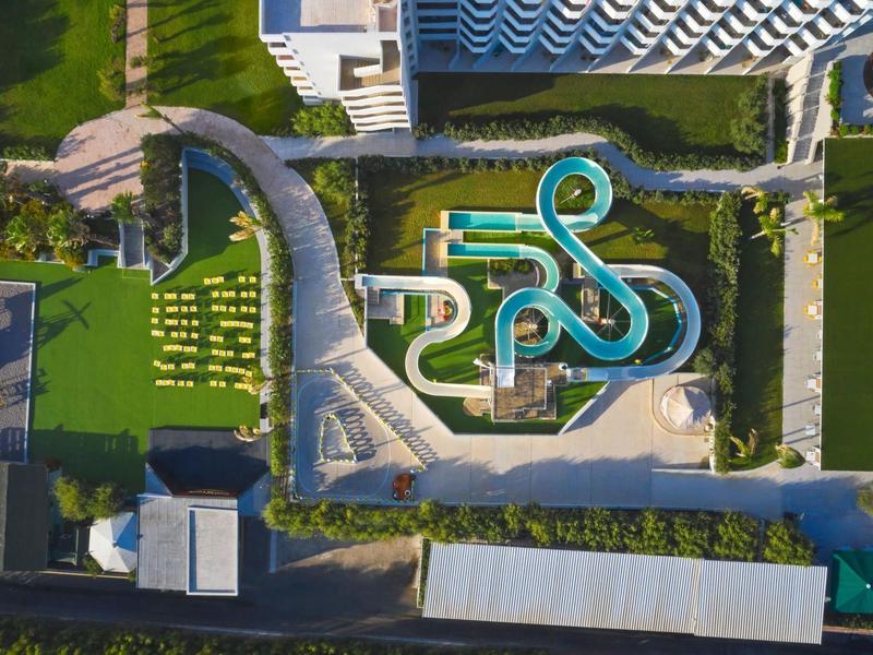 Vogelperspektive eines Wasserparks mit Wasserrutschen und grünen Liegewiesen