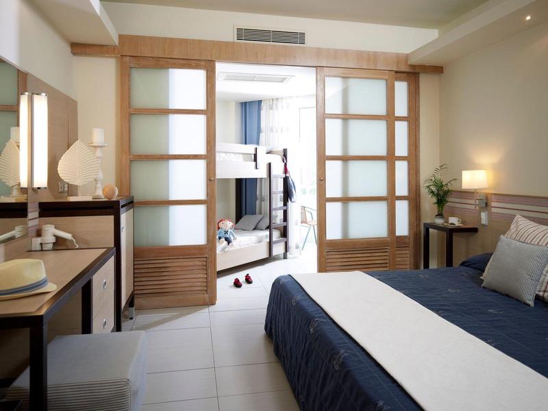 Modernes Hotelzimmer mit Doppelbett, Schiebetüren und Arbeitsplatz mit Stuhl.