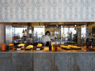 Theke mit Backwaren und einem Mitarbeiter dahinter in einer modernen Bäckerei.