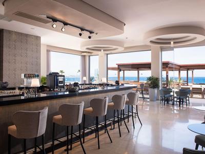 Modernes Hotelrestaurant mit Bar und Blick auf das Meer bei Tageslicht.