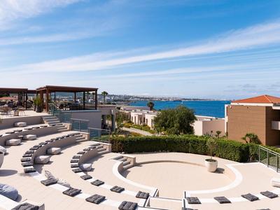 Rundes Freilufttheater mit Stufen und Sitzgelegenheiten mit Blick aufs Meer und Hotelgebäude.