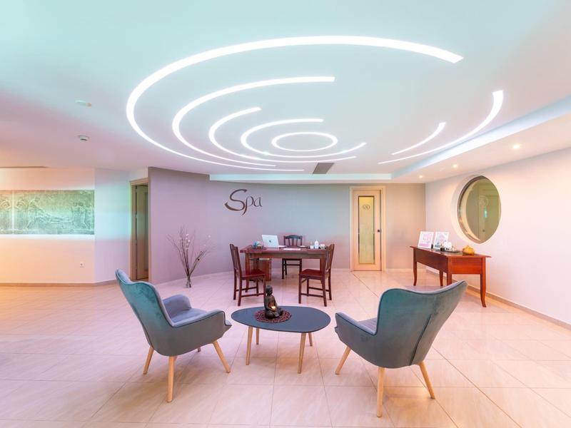 Moderner Warteraum mit hellen Wänden, abgerundeten LED-Deckenlichtern und eleganten Sesseln.