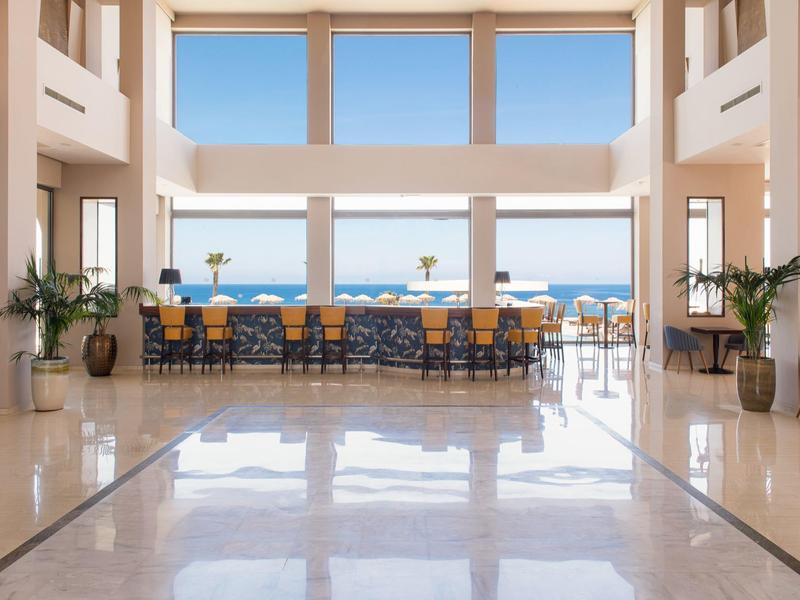 Großer heller Raum mit Marmorboden und Sitzgruppe vor Panoramafenstern mit Meerblick.