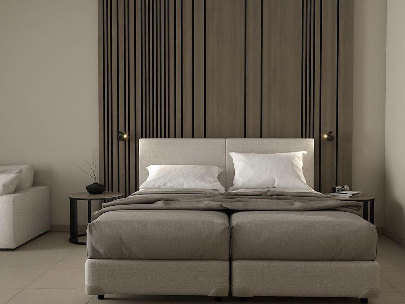 Modernes Schlafzimmer mit gepolstertem Doppelbett, Seitentischen und grauem Sofa.