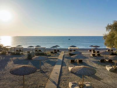 Playa vacía con sombrillas y tumbonas al atardecer sobre el mar tranquilo.