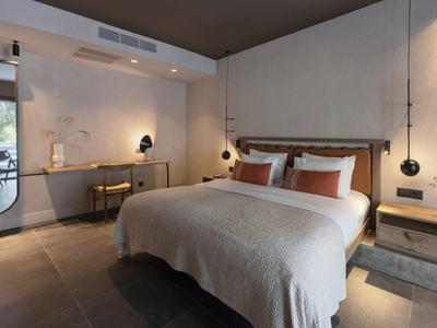 Habitación de hotel moderna con cama grande, escritorio funcional y decoración minimalista en tonos neutros.