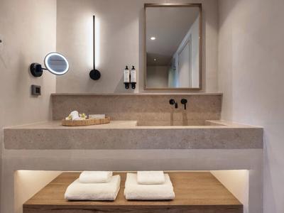 Baño moderno con espejo iluminado, lavabo y toallas limpias debajo del mostrador.