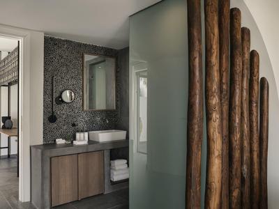 Baño moderno con lavabo, espejo, elementos de madera y toallas en colores neutros.
