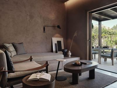 Area salotto moderna con divano, poltrona, tavolino e accesso aperto alla terrazza con vista.