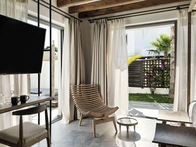 Soggiorno luminoso con sedia di legno e vista su un piccolo giardino.