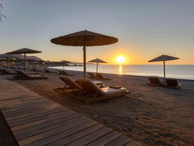Spiaggia con lettini e ombrelloni al tramonto vicino al mare