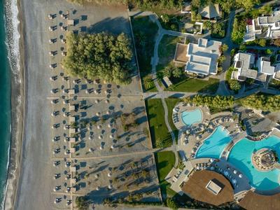 Vista aerea di un resort con piscina, ombrelloni sulla spiaggia e edifici adiacenti.
