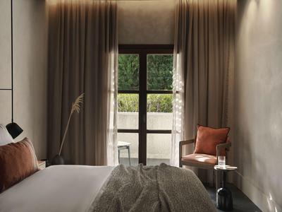 Camera d'hotel accogliente con letto grande, tavolo, sedia e vista sulla terrazza.