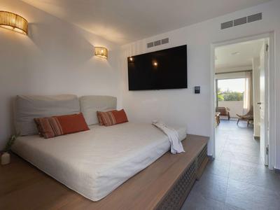 Camera d'hotel moderna con letto matrimoniale, TV a schermo piatto e vista su una stanza adiacente luminosa.