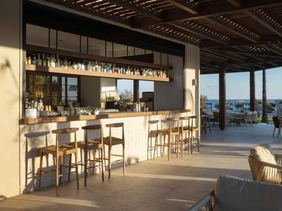 Area bar moderna dell'hotel con sgabelli in legno e vista sul mare al sole.