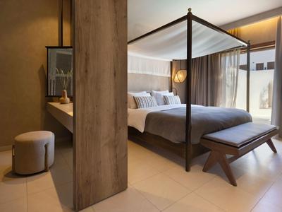 Camera da letto moderna con letto a baldacchino e panca, tonalità calde.