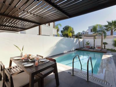 Area esterna moderna con tavolo da pranzo e piscina sotto una pergola in legno.